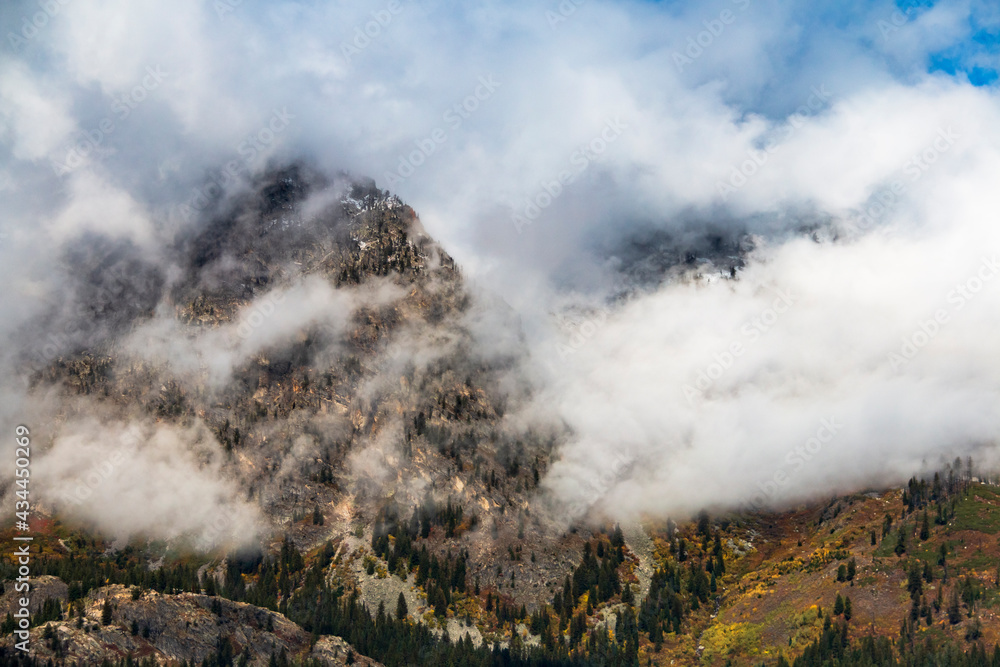 dramatic snow capped jagged peaks of Grand teton mountains surrounded by vibrant autumn foliage of aspen and birch trees in Wyoming. dramatic snow capped jagged peaks of Grand teton mountains surrounded by vibrant autumn foliage of aspen and birch trees in Wyoming.