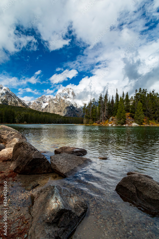 vibrant autumn foliage and snow capped mountains   surround Jenny lake during fall season.