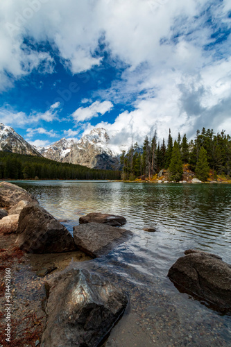 vibrant autumn foliage and snow capped mountains surround Jenny lake during fall season.