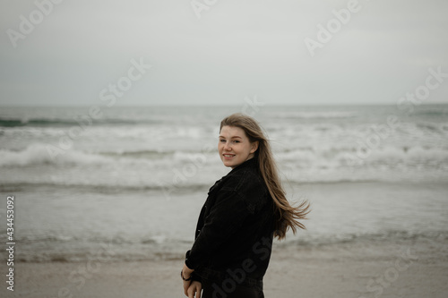 young girl smiling while standing on the beach, hair fluttering © Maxim
