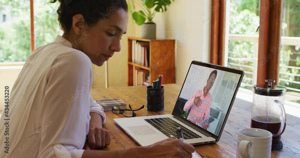 African american woman taking notes while having a video call on laptop at home African american woman taking notes while having a video call on laptop at home