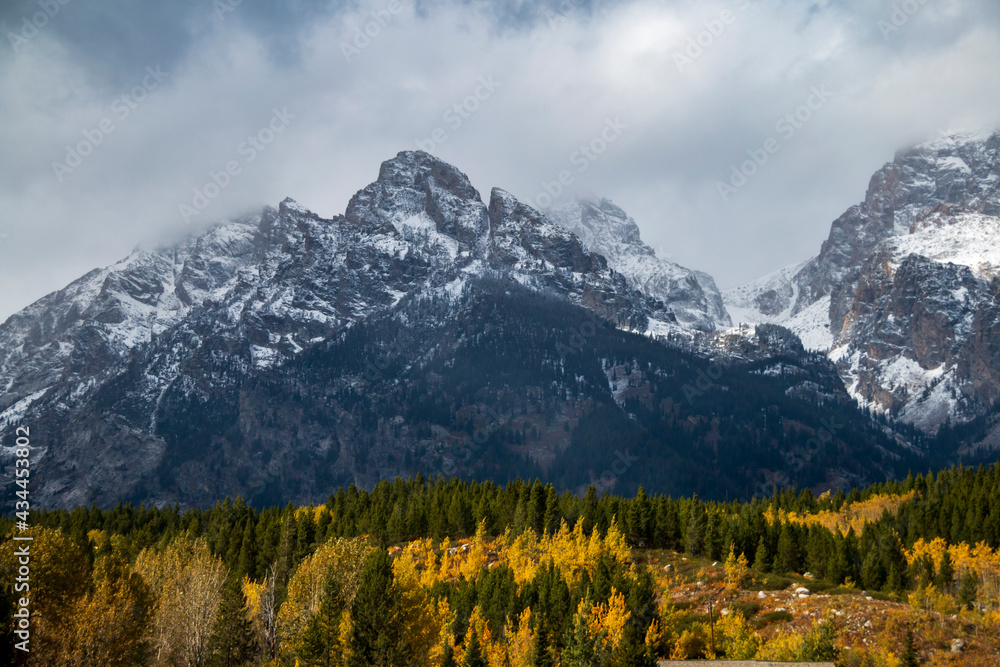 dramatic  snow capped mountain peaks of the Grand teton mountain range and colorful autumn foliage in Jackson, Wyoming.