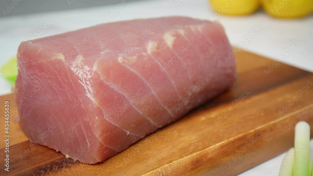 Closeup of raw Tuna Yellowfin on a table with greens and vegetables in 4K. Healthy meat, fresh tuna for steak or salad on a chopping board. Closeup of raw Tuna Yellowfin on a table with greens and vegetables in 4K. Healthy meat, fresh tuna for steak or salad on a chopping board.