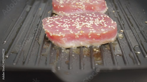 Close-up grilling yellowfin tuna steak on a grilling pan in 4K. Concept frying and cooking tuna steak in slow motion.