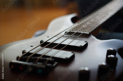 Closeup shot of a smooth body, pickups, bridge, knobs and strings of a bass guitar musical instrument with backlight