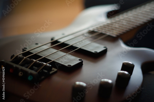 Closeup shot of a smooth body, pickups, bridge, knobs and strings of a bass guitar musical instrument with backlight