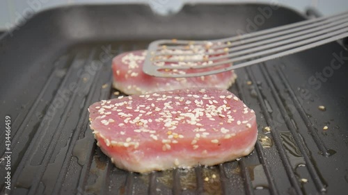 Close-up grilling yellowfin tuna steak on a grilling pan in 4K. Concept frying and cooking tuna steak in slow motion.