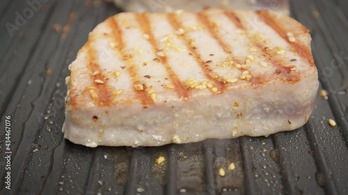 Close-up grilling yellowfin tuna steak on a grilling pan in 4K. Concept frying and cooking tuna steak in slow motion.