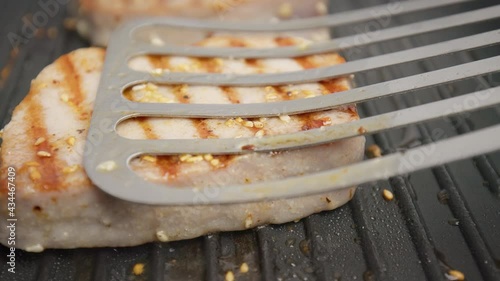 Close-up grilling yellowfin tuna steak on a grilling pan in 4K. Concept frying and cooking tuna steak in slow motion.