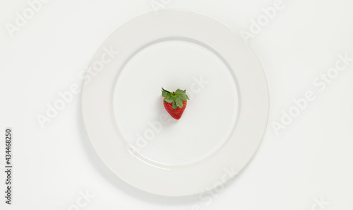 Fresa en plato blanco y mantel blanco
