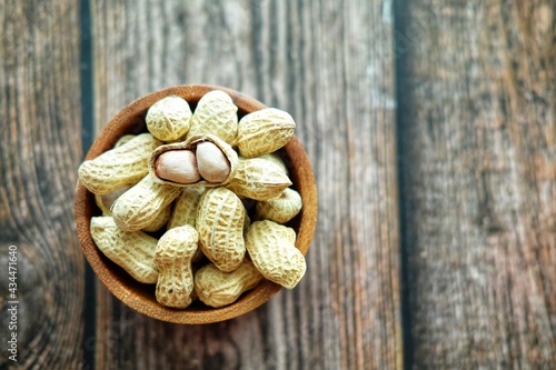 Peanuts on wooden bowl.