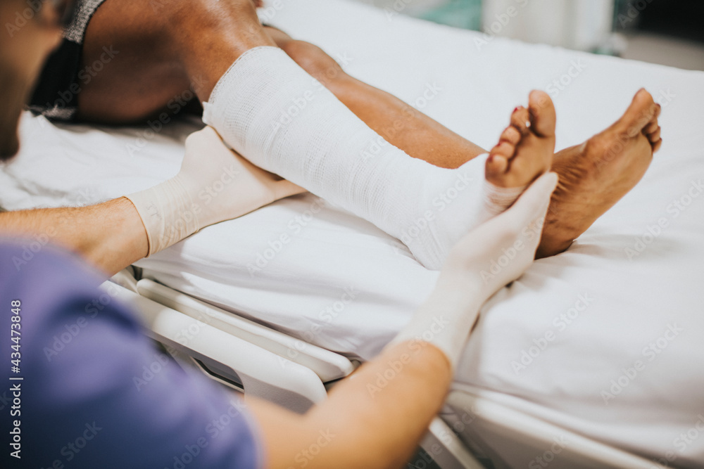 Obraz premium Doctor helping a patient with a fractured leg