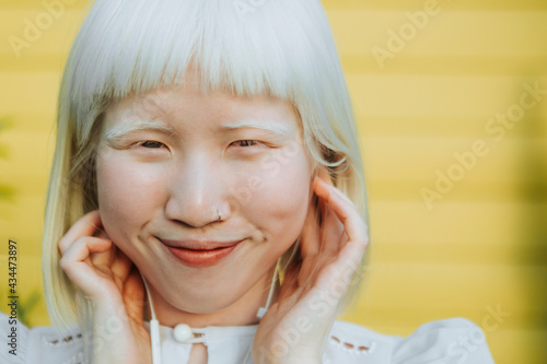 Cute albino girl listening to her favorite music through earphones photo
