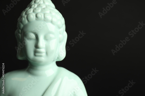 Beautiful ceramic Buddha sculpture on black background. Space for text