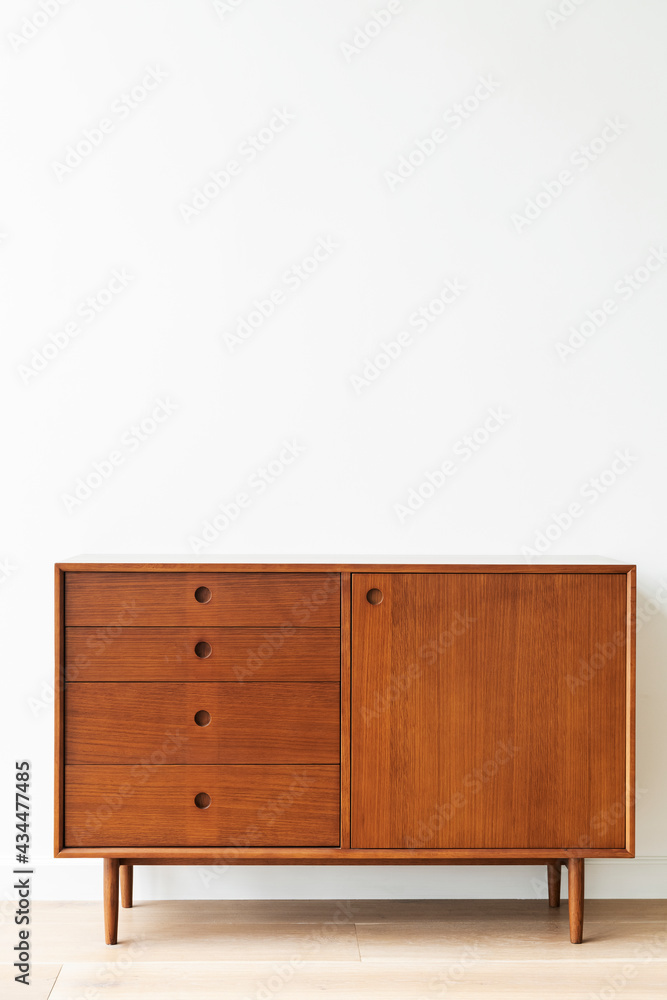 Mid century modern wood cabinet by a white wall Mid century modern wood cabinet by a white wall