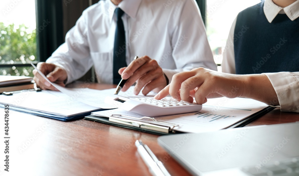 Businessman analyzing investment charts and pressing calculator buttons over documents. Accounting Concept. Businessman analyzing investment charts and pressing calculator buttons over documents. Accounting Concept.