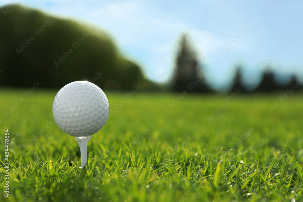 Golf ball on tee at green course, space for text Golf ball on tee at green course, space for text