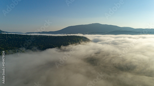 Aerial view  Mist or sea of fog cover the mountains valley. Cloudy view on top of a mount with clouds at foreground and background. ocean of clouds