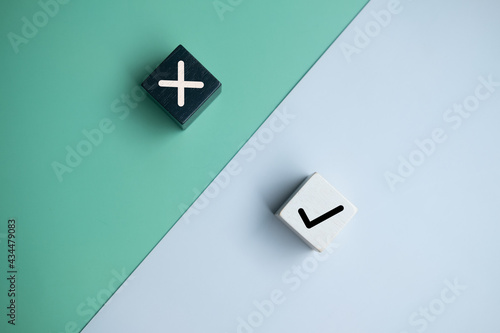 True and false symbols accept rejected on wood cubes for evaluation on a two colored background.