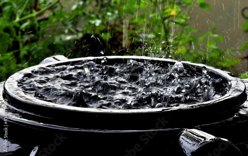 Rainwater harvesting. A collection tank full of rain water, overhead view. A drop rises up in the middle of ripples.
