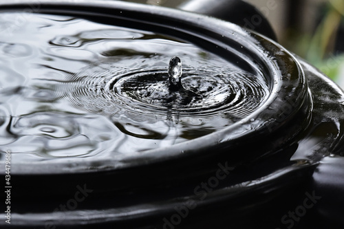 Rainwater harvesting. A collection tank full of rain water, overhead view. A drop rises up in the middle of ripples.
