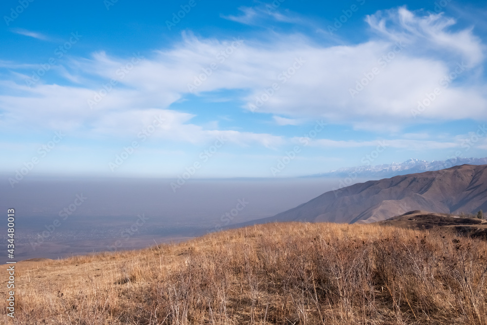 Mountain landscape with smoke on background. Almaty air pollution concept. Ushkonyr plateau, Kazakhstan.