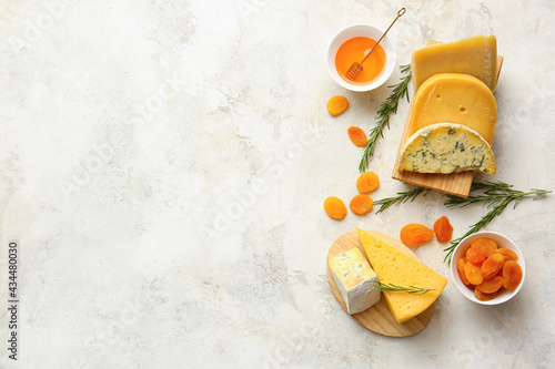 Fotografía Different types of cheese, dried apricots and honey on light background