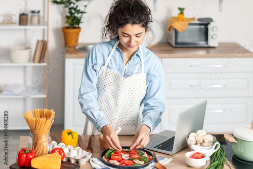 Young woman putting basil i...