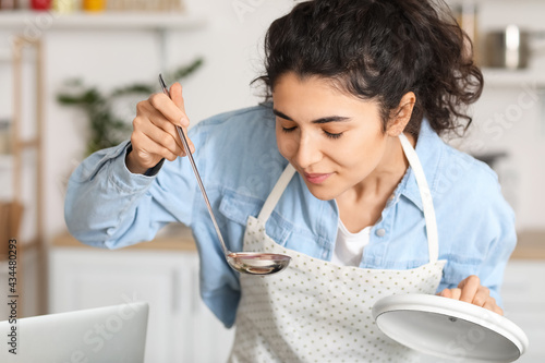 Young woman tasting dish in...
