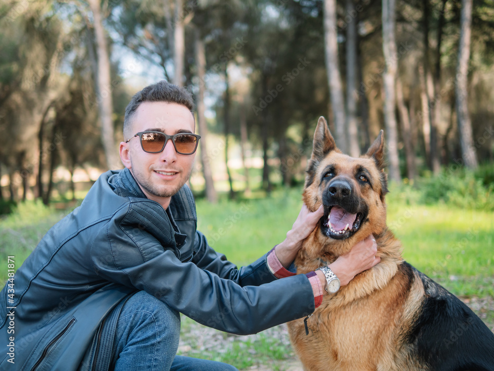 Young man playing with his dog in the forest. Selective focus Young man playing with his dog in the forest. Selective focus
