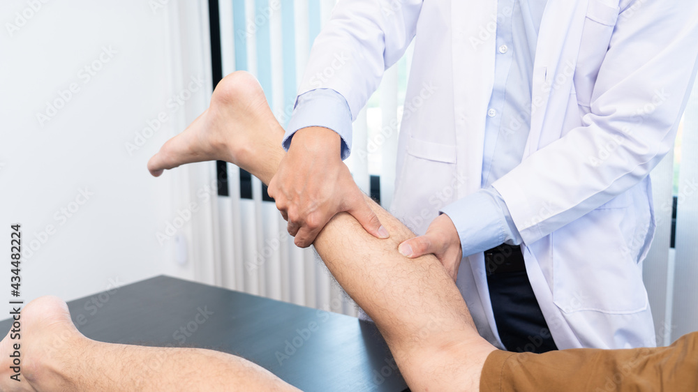Fototapeta premium Medical concept a male doctor diagnosing a male patient's leg by pressing his leg because of playing football