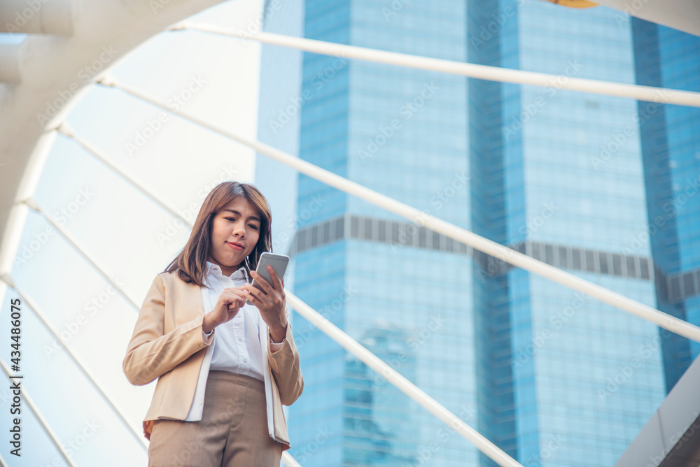 Fototapeta premium Business woman using smartphone shopping online, call, texting message internet technology lifestyle. Asian woman using cellphone walking on city street. Smart phone smart confident woman modern city