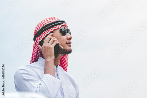 Islamic man using smartphones app organize schedule agenda  focus on hands holding smartphone muslim modern uae city. Arab men wear hijab and muslim formal dress sending text sms online lifestyle photo