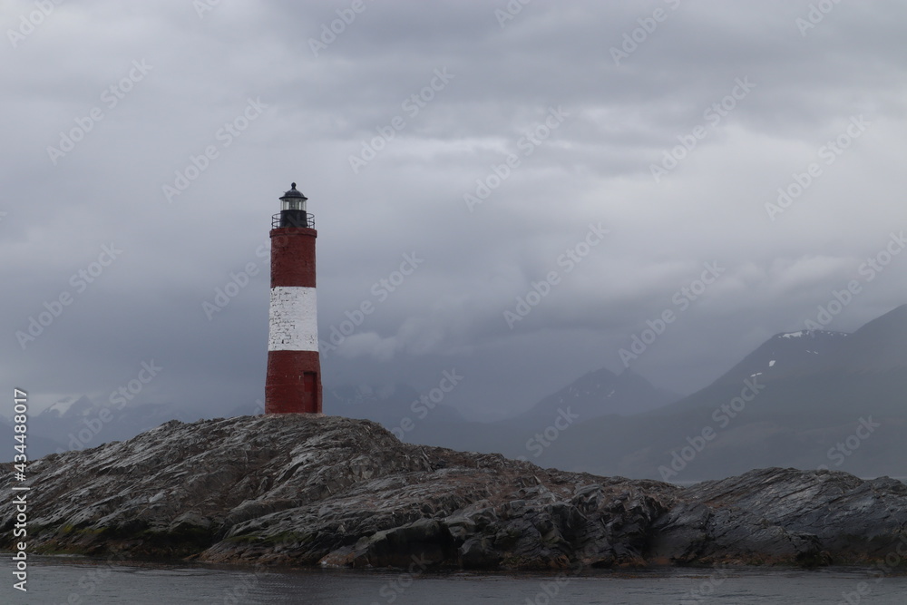 Lighthouse on the end of the world, famous sign in the beagle channel, red and white house to orientate on the ocean, landmark near by the coastline in tierra de fuego patagonia argentina
