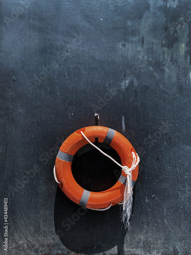 Orange rescue lifebuoy on dark grey background. Minimal travel by sea background