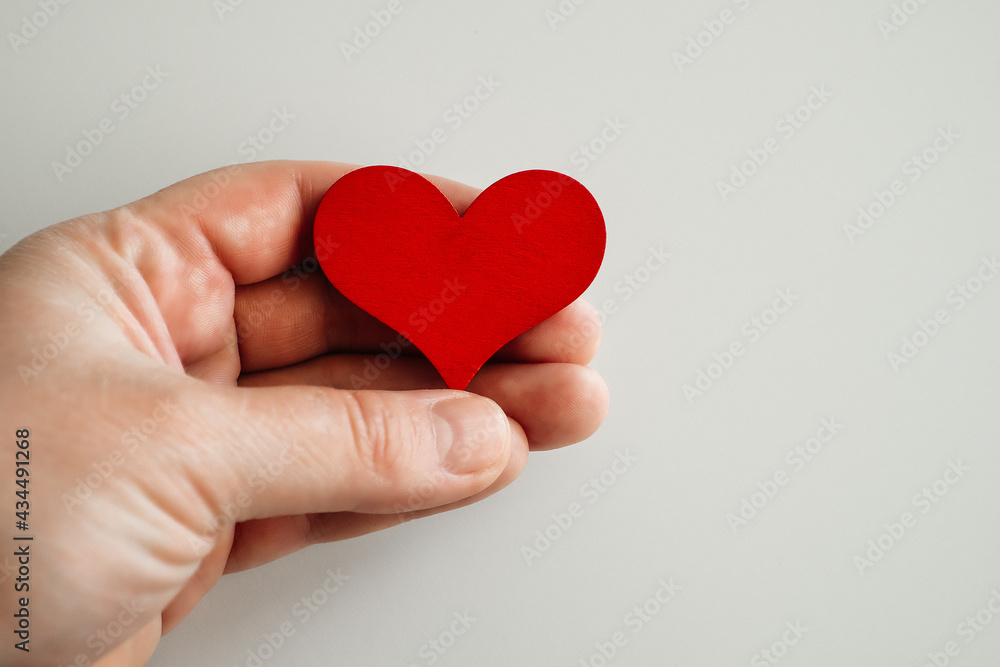 wooden red heart in hand, on a white background wooden red heart in hand, on a white background