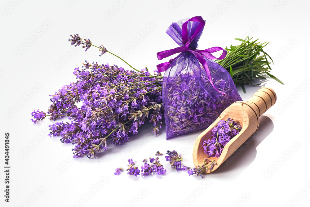 Fragrant bag or pouch with lavender flowers on white background. Sprigs of lavender near the sachet with lavender.