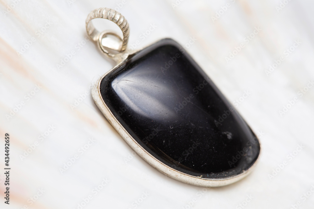 Metal frame mineral stone pendant on white shell background Metal frame mineral stone pendant on white shell background