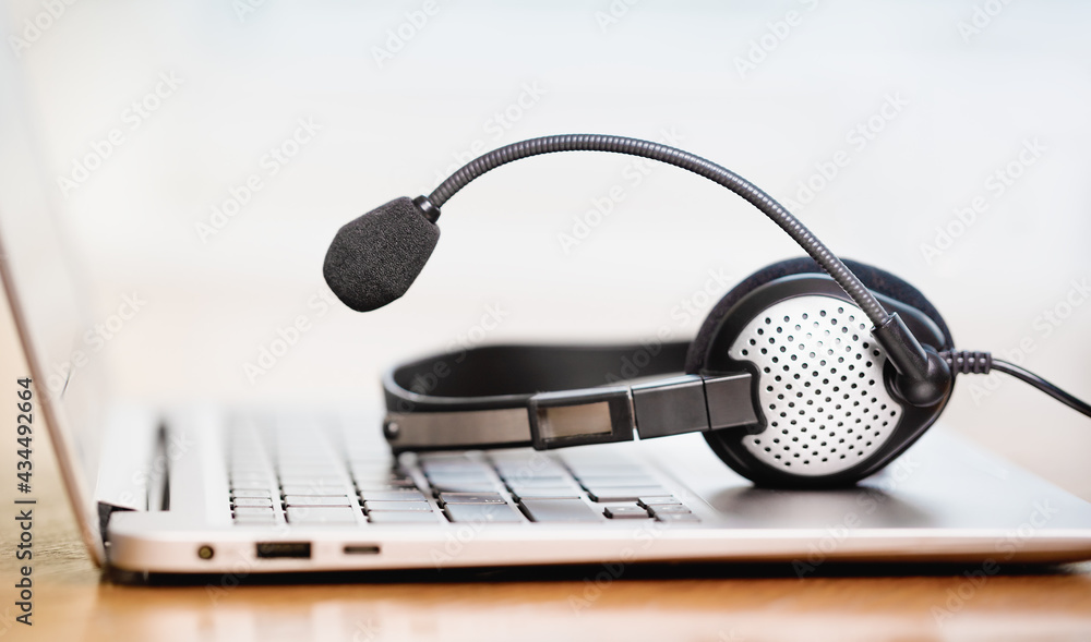 Laptop. Close up of headphones or headset on desk and plain background banner. Distant learning or working from home, online courses or customer support minimal concept. Helpdesk or call center Laptop. Close up of headphones or headset on desk and plain background banner. Distant learning or working from home, online courses or customer support minimal concept. Helpdesk or call center
