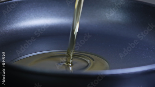 Pan with oil. Cook pours sunflower oil into a frying pan, macro shot.  Olive oil is poured into a frying pan.
