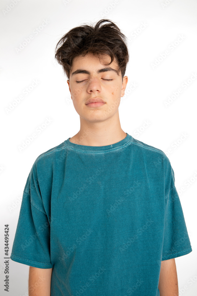 Portrait of teenager on white background in studio. The boy is standing and has his eyes closed. Portrait of teenager on white background in studio. The boy is standing and has his eyes closed.