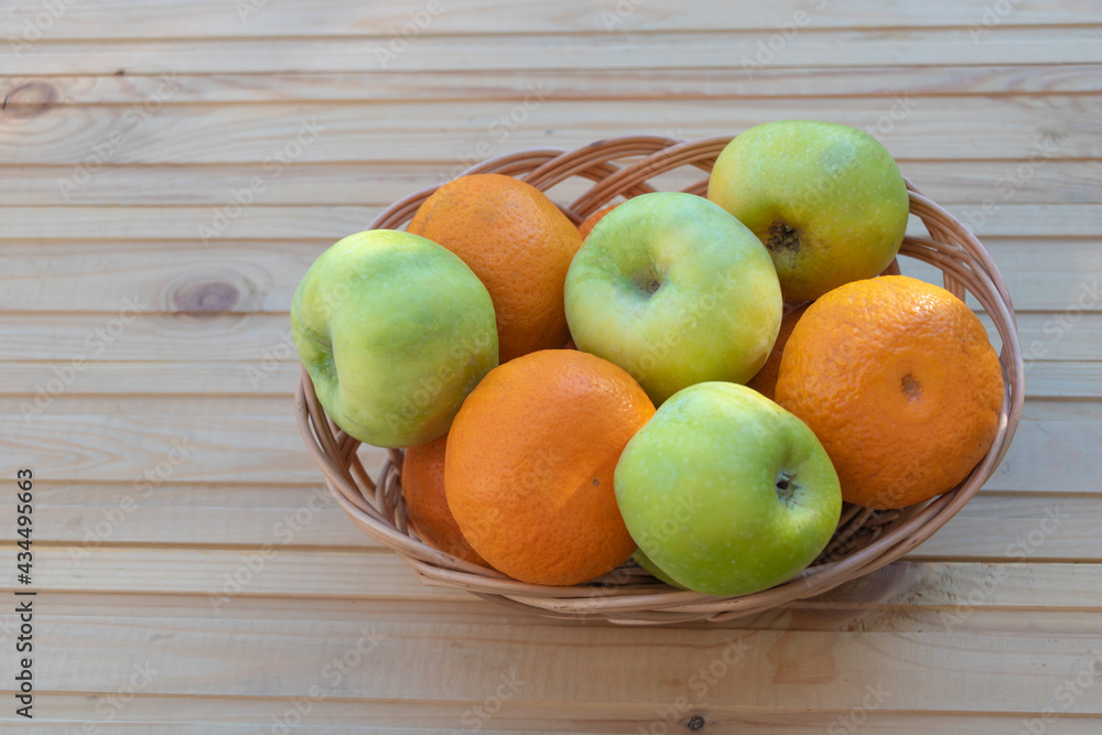Oranges and apples in a basket on wooden background Oranges and apples in a basket on wooden background