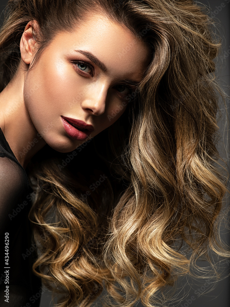 Naklejka premium Portrait of a beautiful woman with a long hair. Pretty blonde girl with curly hairstyle.