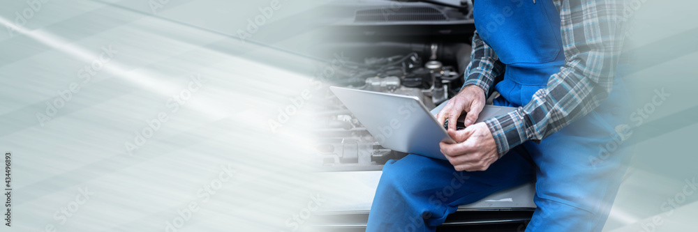 Mechanic using laptop for checking car engine; panoramic banner