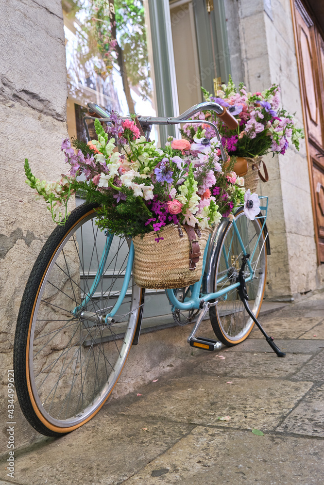 vintage bicycle decorated with wicker baskets hanging from the handlebars full of beautiful flowers, girona flower festival , temps de flors, catalonia, spain