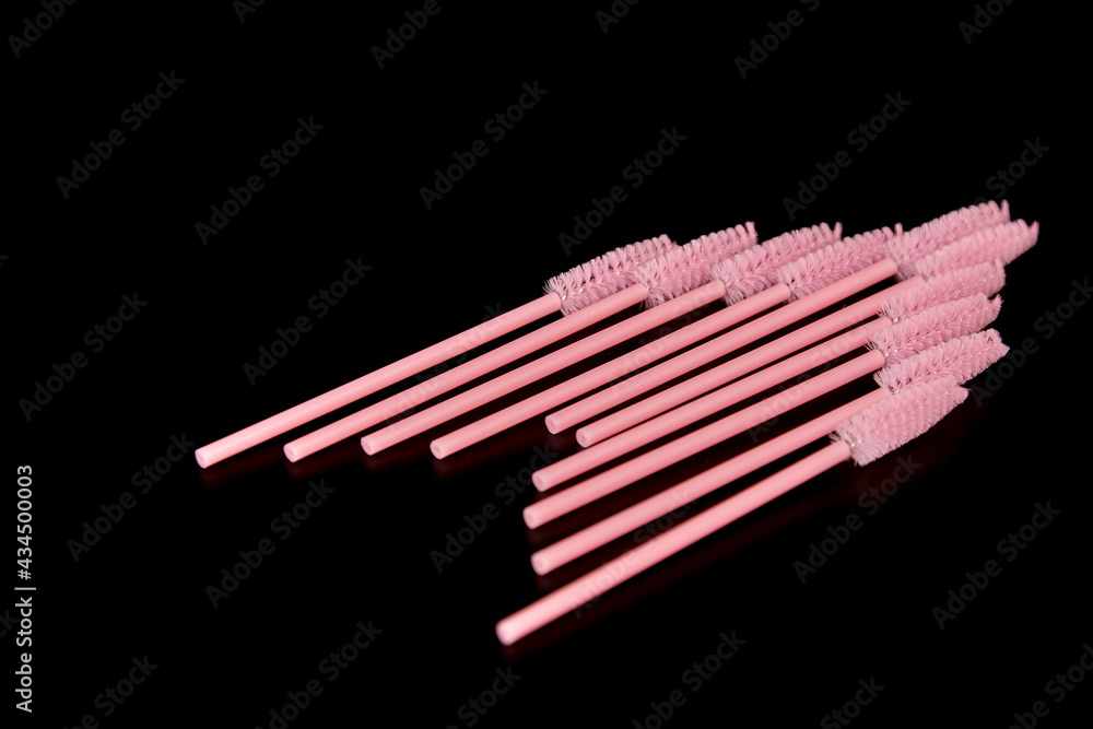 Pink eyelash brushes on a black background. Cosmetic accessories for eyelash extensions Pink eyelash brushes on a black background. Cosmetic accessories for eyelash extensions