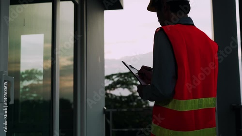 silhouette Contractor checking the building structure specifications on evening. civil engineer record information of nonconforming of house on paper. concept home inspection service and contractor.