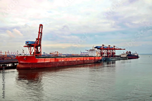 Seagoing vessels, tugboats at the port under cargo operations and underway. Port of Fangcheng, China. September, 2020 photo