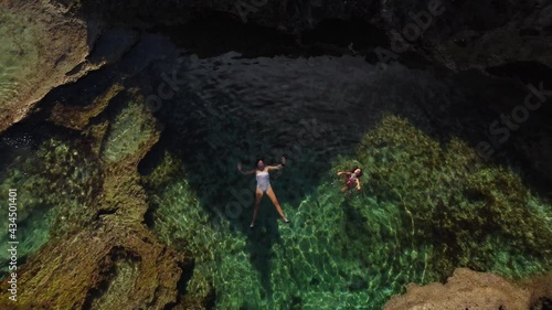 Mom and daughter swim in natural ocean pool at Cap Des Pins. Aerial zoom out. photo