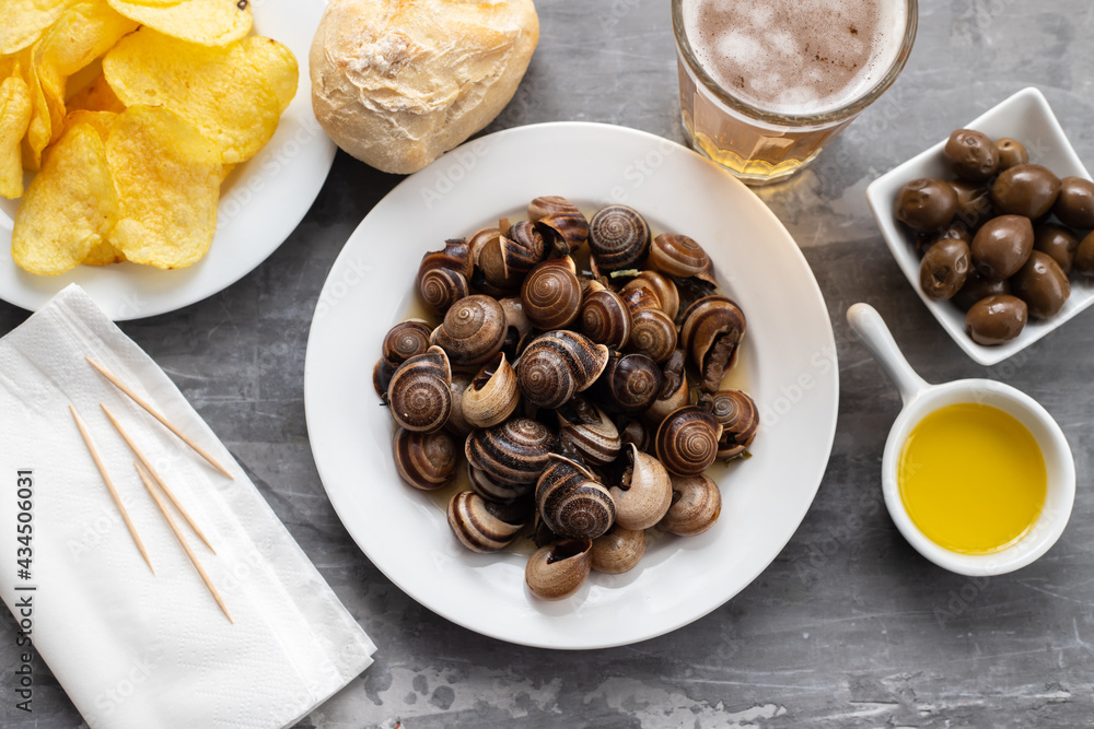 Fototapeta premium boiled snails with bear, bread, olives and potato chips on blue